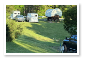 covered wagon with trucks and trailers parked beside it
